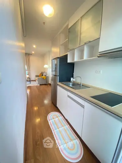 Modern kitchen with sleek cabinetry and open layout leading to cozy living room.