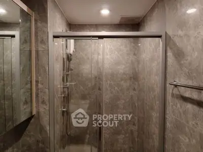 Modern bathroom with sleek glass shower enclosure and elegant marble walls.