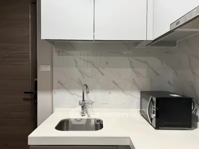 Modern kitchen with sleek white cabinetry and marble backsplash