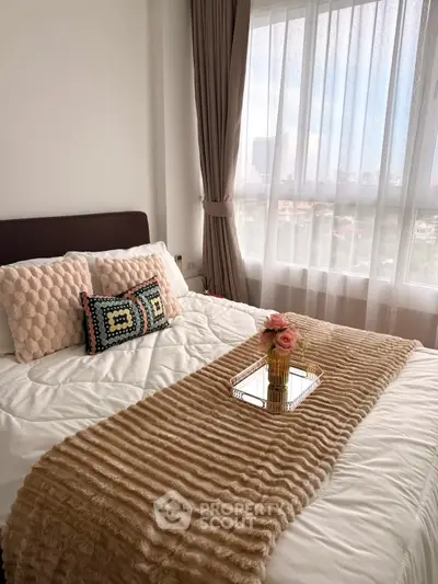 Cozy bedroom with plush bedding and city view through large window