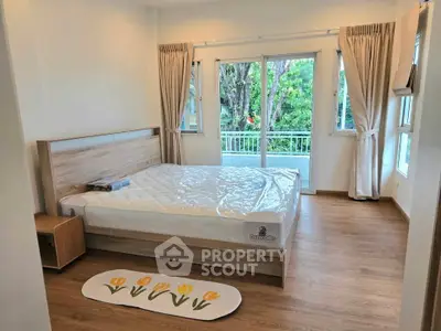 Spacious bedroom with large windows and balcony access, featuring a cozy wooden floor and modern bed.
