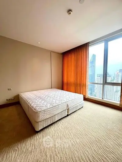 Spacious bedroom with large window offering stunning city views in modern apartment.