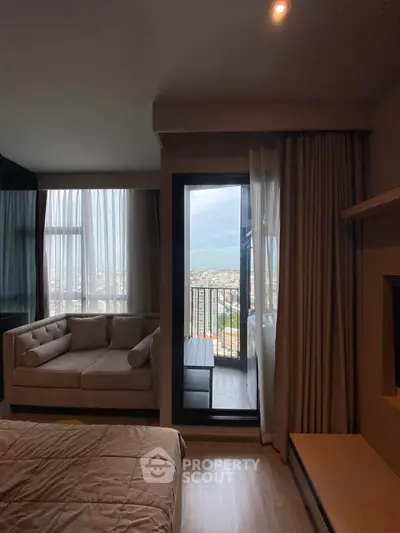 Modern bedroom with cozy sofa and balcony offering stunning city view