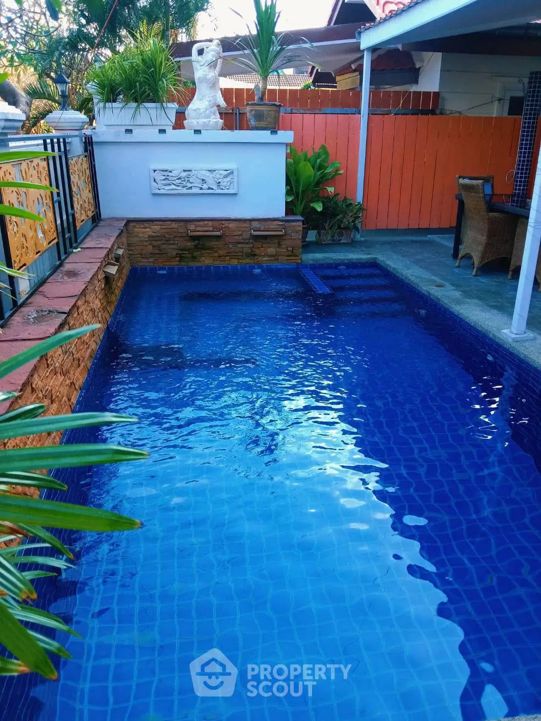 Charming backyard pool with elegant stone accents and lush greenery, perfect for relaxation and entertainment.