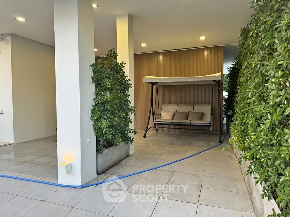 Modern outdoor seating area with swing and lush greenery