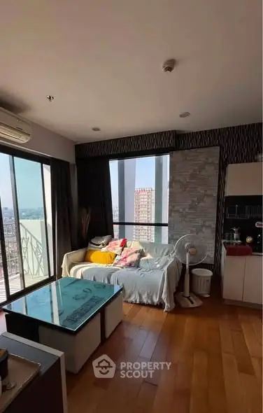 Modern living room with city view, cozy sofa, and stylish decor in high-rise apartment.