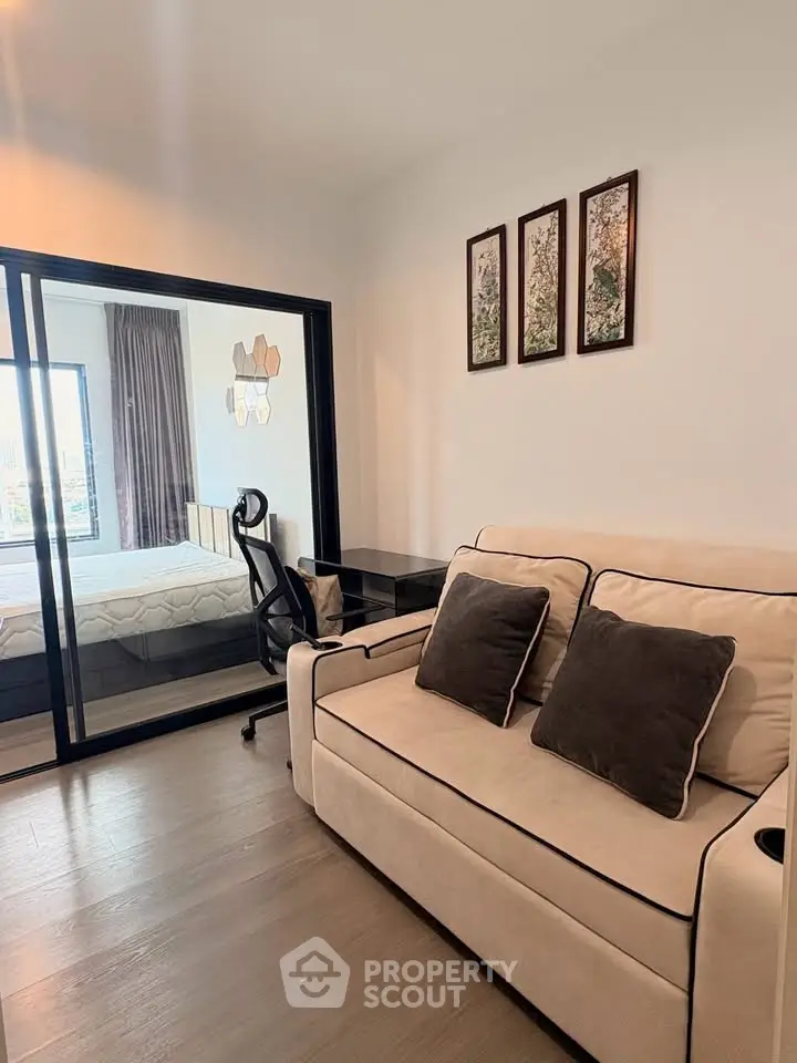 Modern apartment with cozy living room and stylish bedroom separated by glass wall.