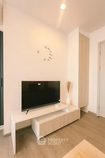 Modern living room with minimalist decor and wall-mounted TV, featuring sleek wooden flooring and stylish storage.