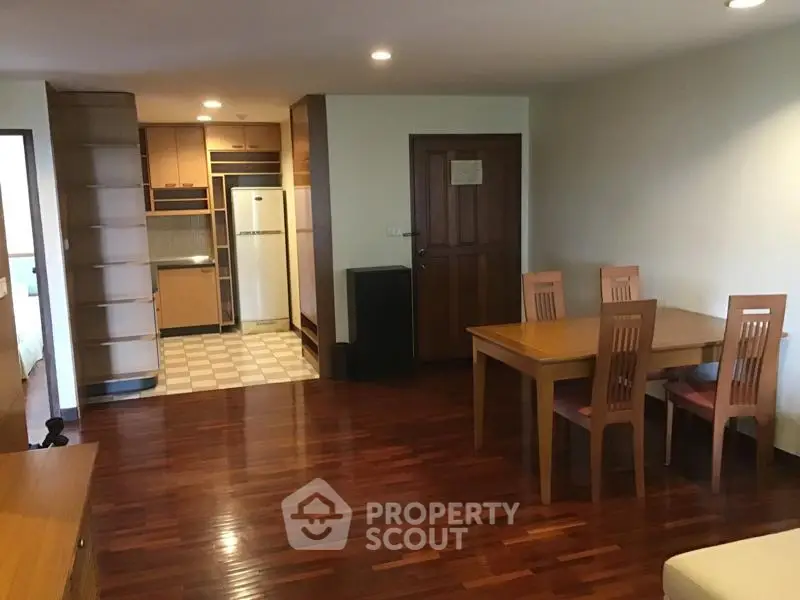 Spacious open-plan living room with wooden flooring and modern kitchen area.