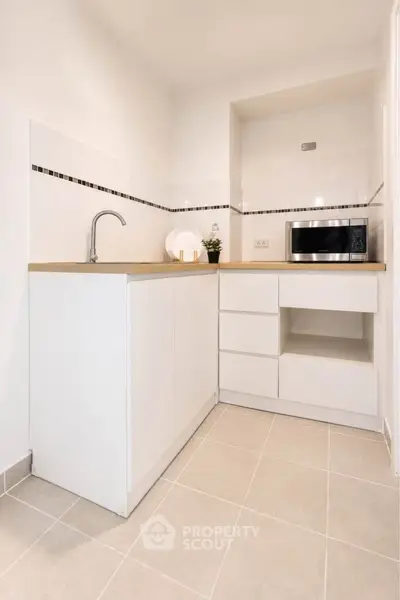 Modern minimalist kitchen with white cabinetry and built-in microwave