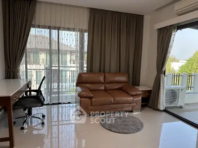 Spacious living room with leather sofa and balcony view in modern apartment