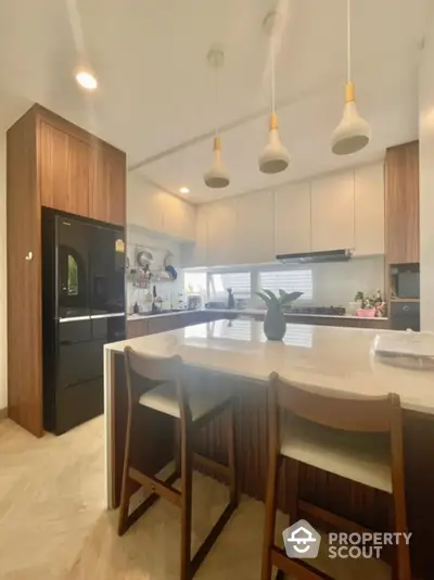 Modern kitchen with sleek design, featuring island seating and contemporary lighting.