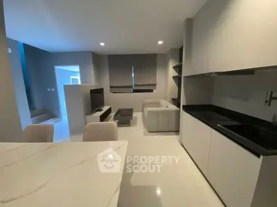 Modern open-plan living room with sleek kitchen and cozy seating area, perfect for contemporary living.