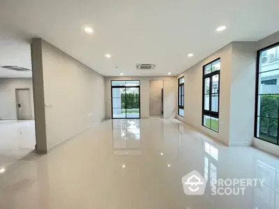 Spacious and bright living room with glossy floor, large windows offering ample natural light, and a view of greenery, perfect for modern living.