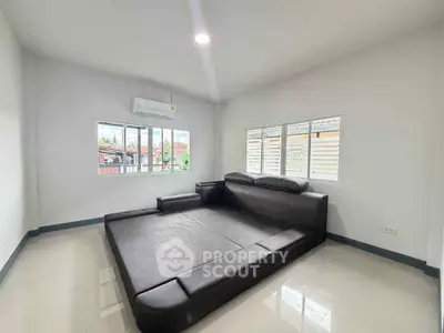 Spacious modern living room with large black sectional sofa and bright windows.