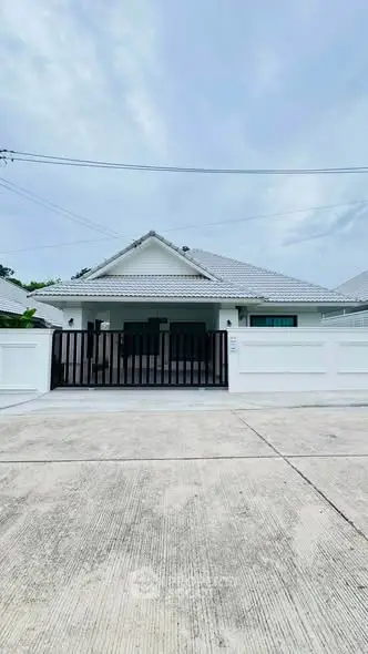 Charming single-story house with white exterior and gated entrance, perfect for family living.