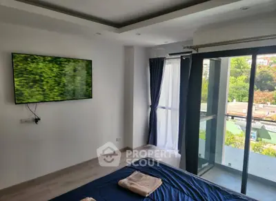 Modern bedroom with large window and wall-mounted TV, offering a serene view of greenery.