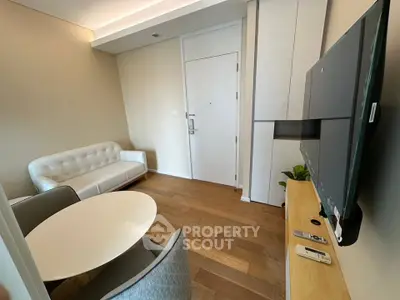 Modern living room with sleek furniture and wooden flooring, featuring a wall-mounted TV and stylish decor.