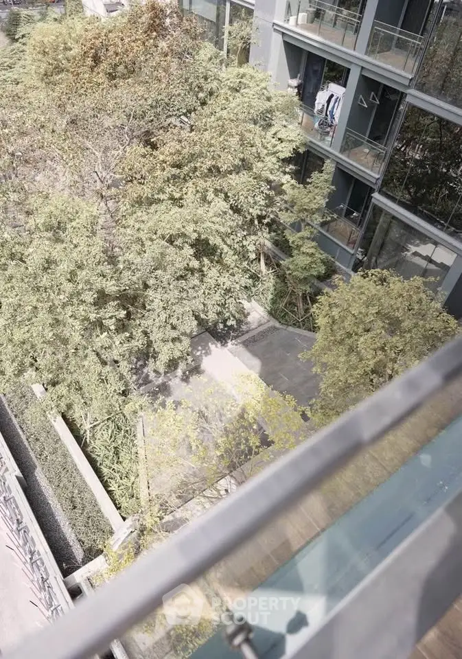 Modern building exterior with lush greenery and glass balconies, offering a serene urban living experience.