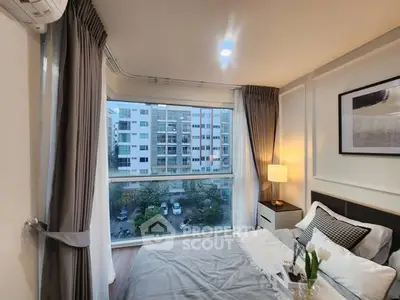 Modern bedroom with large window offering city view, elegant decor, and cozy ambiance.