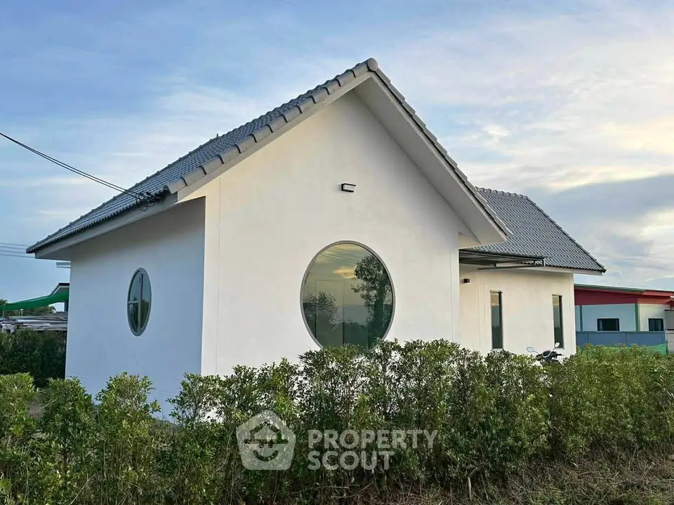 Charming modern house with unique circular windows and lush greenery, perfect for serene living.