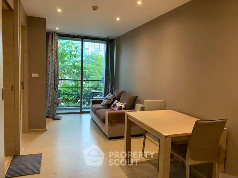 Modern living room with cozy sofa, dining table, and large window overlooking greenery.