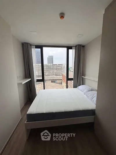 Modern bedroom with large window offering city view, minimalist design and natural light.