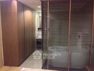 Modern bathroom with sleek wooden paneling and glass partition for a luxurious feel.