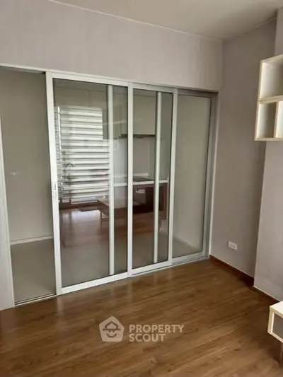Modern room with sliding glass doors and wooden flooring, ideal for versatile living space.