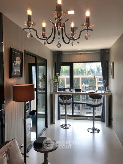 Stylish modern living room with chandelier and large windows offering natural light.