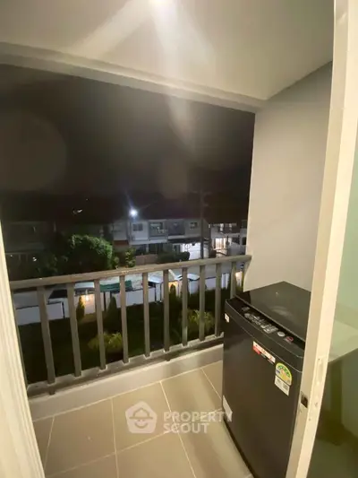 Cozy balcony with washing machine and night view of residential area.