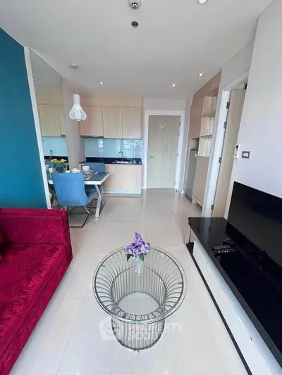 Modern living room with vibrant red sofa and sleek kitchen in open layout apartment.