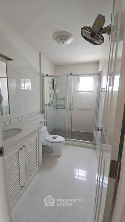 Spacious bathroom with modern fixtures and glass shower enclosure in a bright apartment.