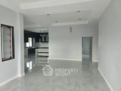 Spacious modern living room with open kitchen layout and sleek tile flooring.