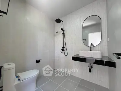 Modern bathroom with sleek fixtures and minimalist design, featuring a stylish shower and elegant sink.