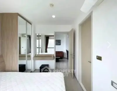 Modern bedroom with sleek design and ample natural light, featuring a mirrored wardrobe and minimalist decor.