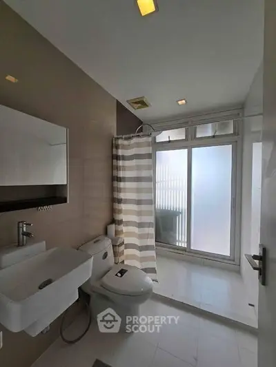 Modern bathroom with sleek fixtures and large frosted window for natural light.
