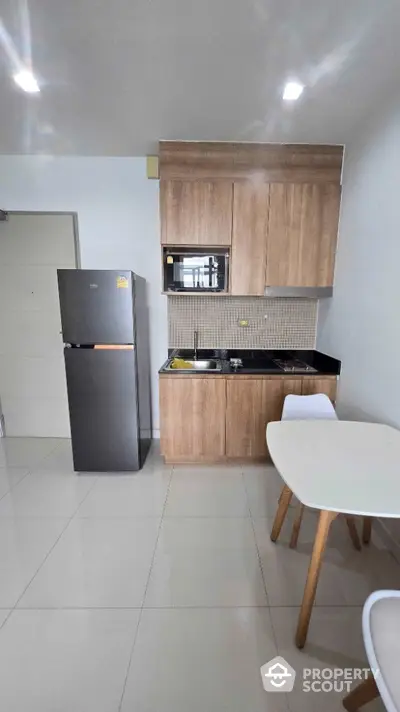 Modern kitchen with sleek cabinetry and compact dining area in a stylish apartment.