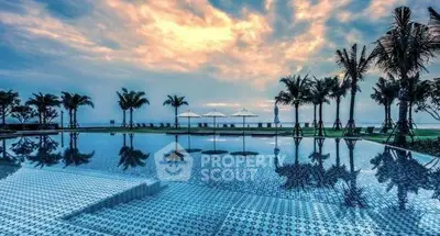 Luxurious beachfront pool with stunning ocean view and palm trees at sunset.