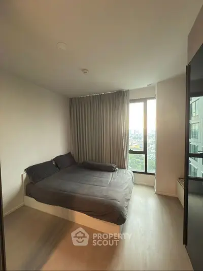 Modern bedroom with large window and city view, featuring sleek design and natural light.