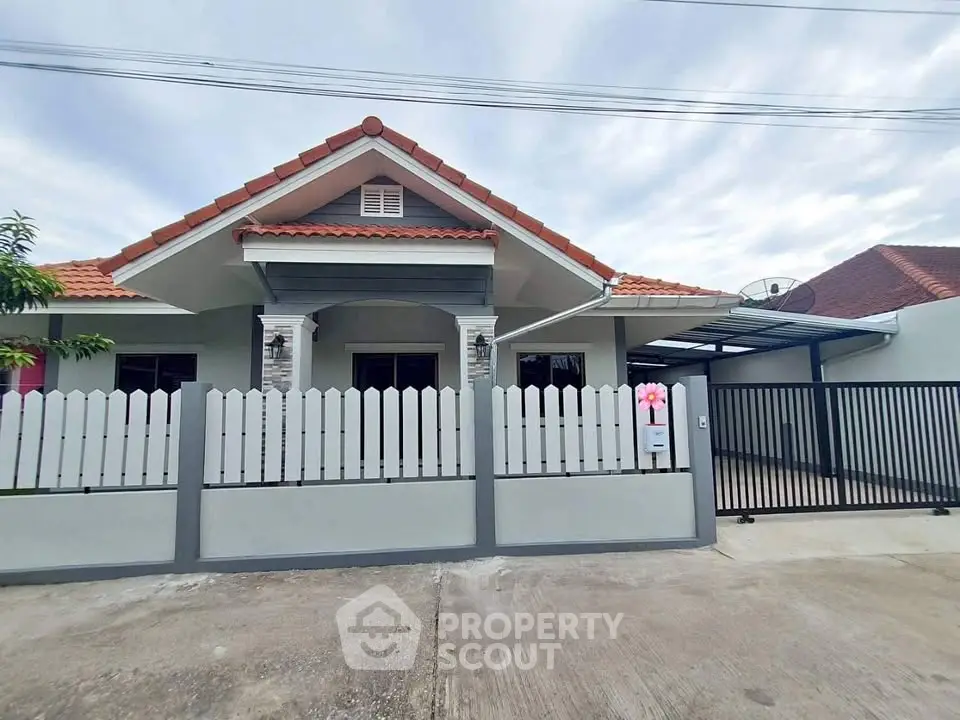 Charming single-story house with a fenced yard and carport, featuring a red-tiled roof and modern design.