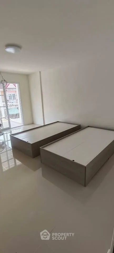 Spacious bedroom with twin beds and natural light from large window.