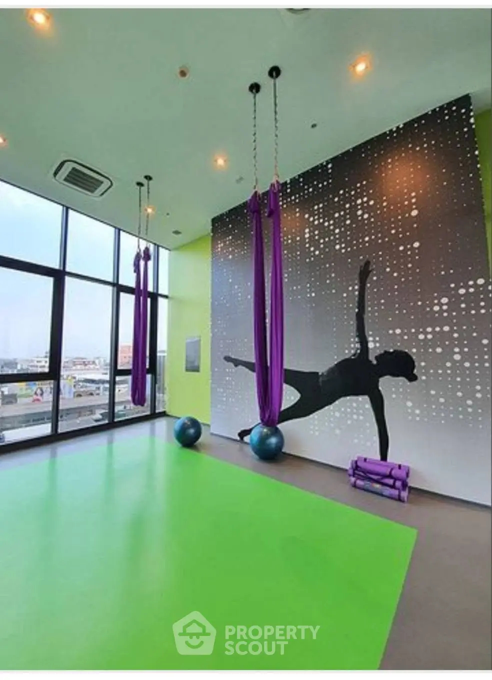 Modern gym with aerial yoga setup and panoramic city view, perfect for fitness enthusiasts.