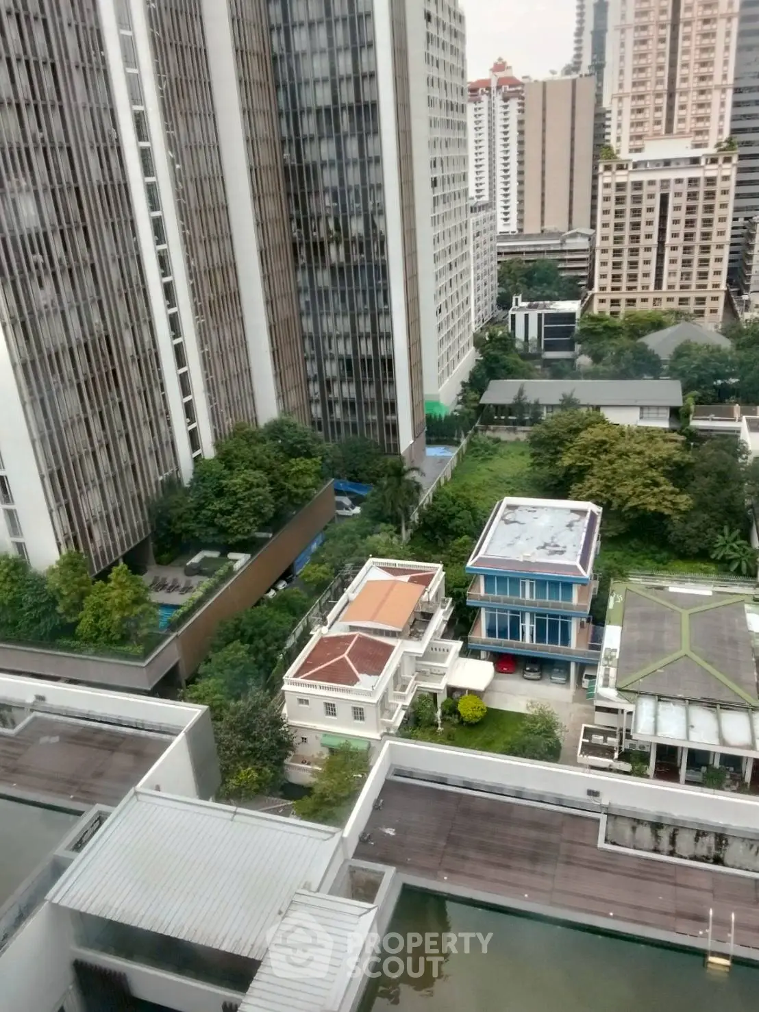 Stunning cityscape view from high-rise building showcasing urban architecture and lush greenery.