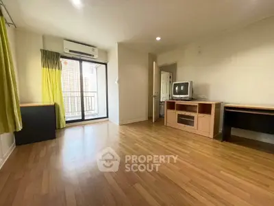 Spacious living room with wooden flooring and balcony access in modern apartment.
