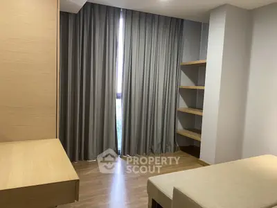 Modern minimalist room with wooden flooring and built-in shelves, featuring elegant curtains and a cozy ambiance.