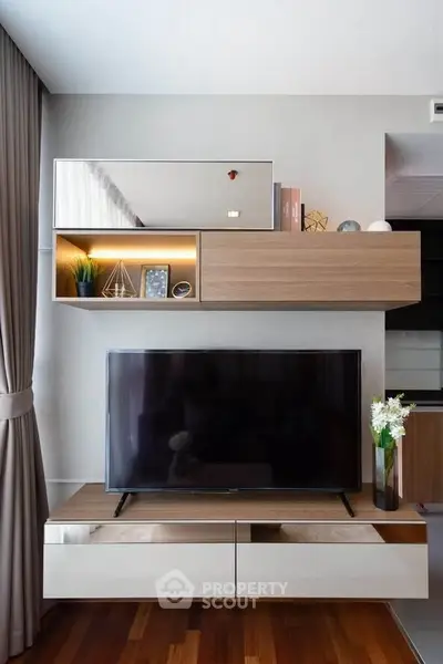 Modern living room with stylish wooden TV unit and decorative shelves.