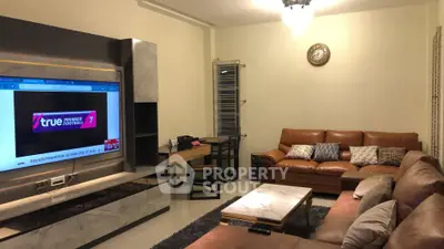 Spacious living room with modern decor and large TV, perfect for relaxation and entertainment.