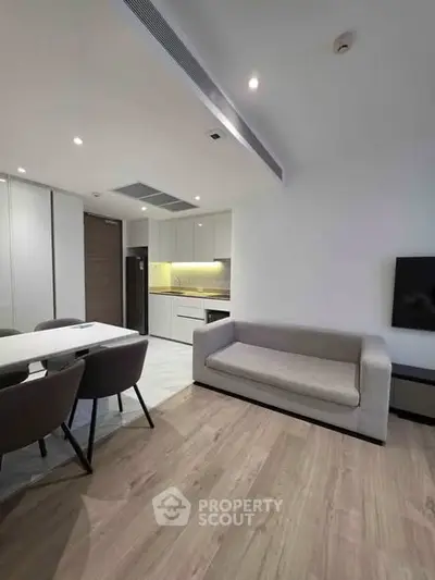 Modern open-plan living room with sleek kitchen and stylish dining area in contemporary apartment.
