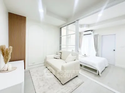Modern open-layout living room with cozy sofa and bright bedroom view